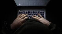 Person with a hoody typing at a computer in the dark. Suspicious online behavior