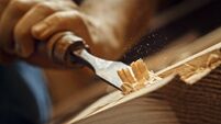 Carpenter shapes wood with chisel