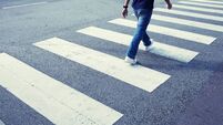 Man in jeans walking across a zebra crossing