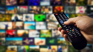 tv channels in background and remote control in hand. smart television and content on demand concept