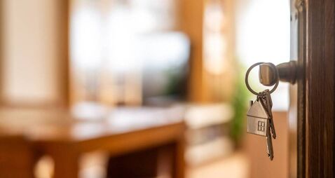 iStock-2204074098.jpg House keys with house shaped keychain hanging on a door, opening to a new home, representing real estate investment, purchase, m