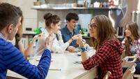 Many Students sitting at Wood Table of Campus and talking