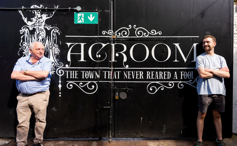 The father and son beside a proud slogan for the town of Macroom.