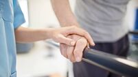 Female nurse touching senior man's hand on railing