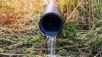 Level view close-up at a land drain pipe with slow flow