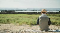 iStock-2168207516.jpg Senior men past retirement age relax and enjoy their hobbies on a sandy beach.