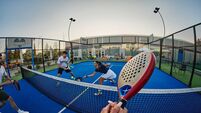 Friends playing padel on a blue outdoor court — energetic POV shot of group sport and recreation
