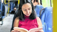 Young woman reading a book while commuting by bus