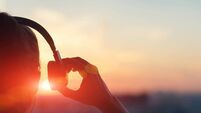Girl in headphones listening to music in the city at sunset