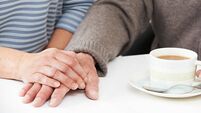 Close Up Of Woman Sharing Cup Of Tea With Elderly Parent