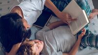 Mother and preteen son lying on bed and reading