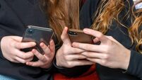 teenage school girls being cyber bullies  or just catching up on social media both on there phones, hand level  copy space above