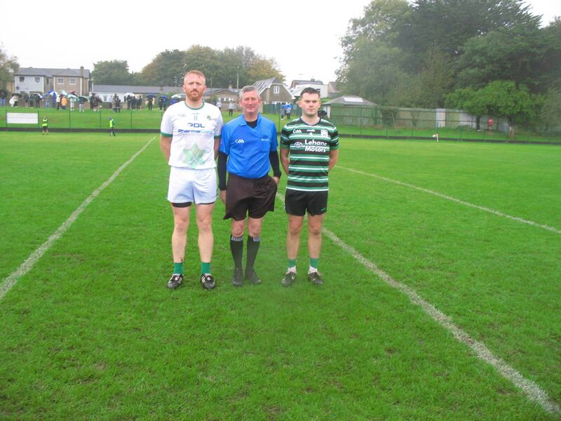 Referee Mark Maher accompanied by captains, James Kind (Passage) and Joe Cremin (Douglas) Referee Mark Maher accompanied by captains, James Kind (Passage) and Joe Cremin (Douglas)