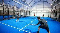 Group of skilled padel players playing padel match on new court indoors at night