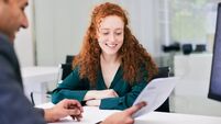 The office worker presents a document to the client across the desk.
