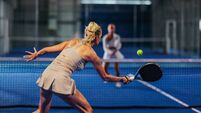 Rear view of a female padel player hitting a forehand