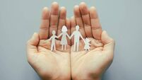 Hand holding family paper cut on blue background. Family day concept, foster care, domestic violence, homeschool, international