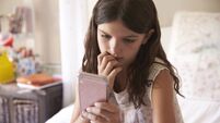 Young Girl In Bedroom Worried By Bullying Text Message