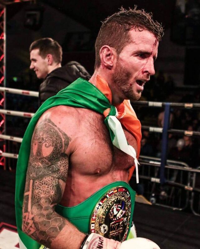Muay Thai fighter Sean Clancy with his belt and the Irish flag after a successful fight.