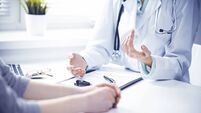 Doctor and  female patient sitting at the desk and talking  in clinic near window. Medicine and health care concept. Green is ma