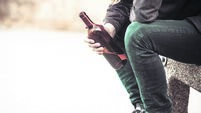 Man depressed with wine bottle sitting on bench outdoor