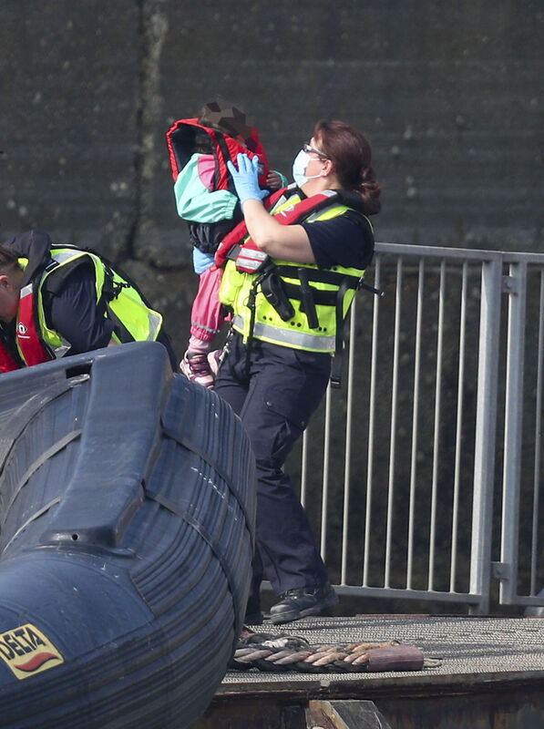 A group of people, including a child, thought to be migrants are brought into Dover, Kent, by Border Force officers.