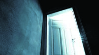 Dark hallway with an opened door with bright light coming in
