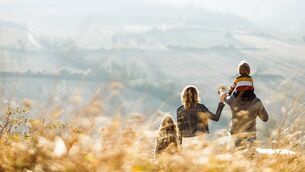 Rear view of a family standing on a hill in autumn day.