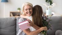 Happy senior grandma hugging granddaughter thanking for gift and flowers