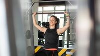 Young woman lifting weight in gym.