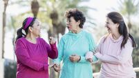 Three Hispanic women walking and talking in park