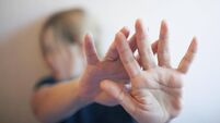 A young woman protects herself by exposing her hand in front of her