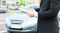 close up of man with car documents outside