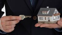 Businessman giving a key and holding small house in hand.