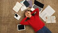Tired student girl lying on the floor with books and gadgets
