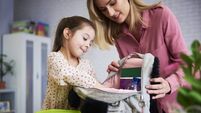 Young mum and daughter packing backpack for the school