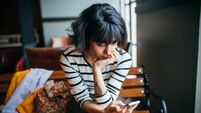 Happy woman using phone at cafe