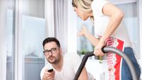 Woman doing chores while man watching tv