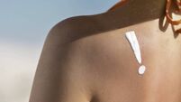 Tanned young woman in bikini showing exclamation point on shoulder due to sunburn,  tan line and reddish skin