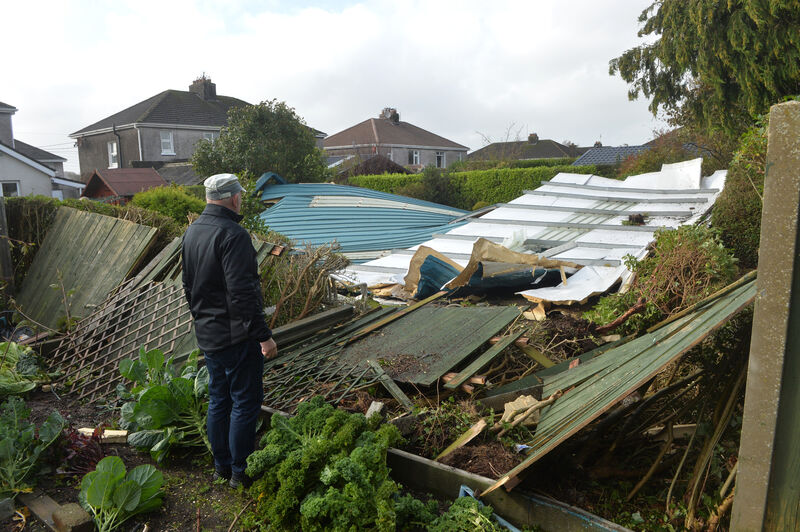 Brendan Coleman looking at a section of the roof off the Douglas Community School gym which was blown through his garden in the height of the hurricane Ophelia. Picture Dan Linehan