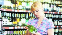 woman choosing and shopping wine at supermarket