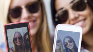 <p>Portrait of three friends taking photos with a smartphone</p>