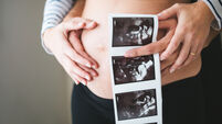 Couple hands holding ultrasound images on the pregnant belly