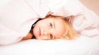Sleepy and tired girl under blanket in bed