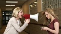 Woman yelling through a bullhorn at an unfazed teenage girl