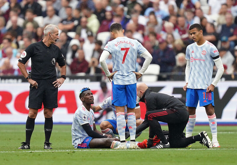 Referee Martin Atkinson (left), Manchester United's Cristiano Ronaldo and Mason Greenwood look on as Paul Pogba receive treatment for an injury during the Premier League match against West Ham at the London Stadium, London. Picture: Mike Egerton/PA Wire.