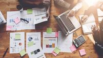 Business People Meeting using laptop computer, calculator, notebook, stock market chart paper for analysis Plans to improve qual