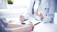 Doctor and  female patient sitting at the desk and talking  in clinic near window. Medicine and health care concept. Green is ma