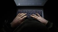 Person with a hoody typing at a computer in the dark. Suspicious online behavior