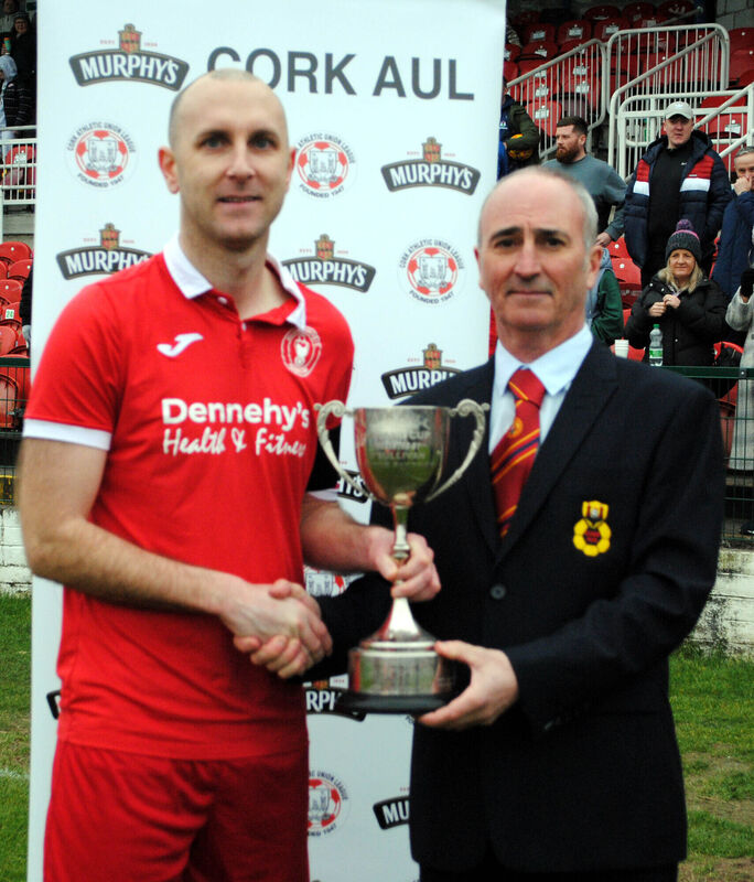 Cathal Hughes (Cork AUL) hands over the Saxone Cup to Killumney United captain Dave McCarthy. Picture: Barry Peelo.